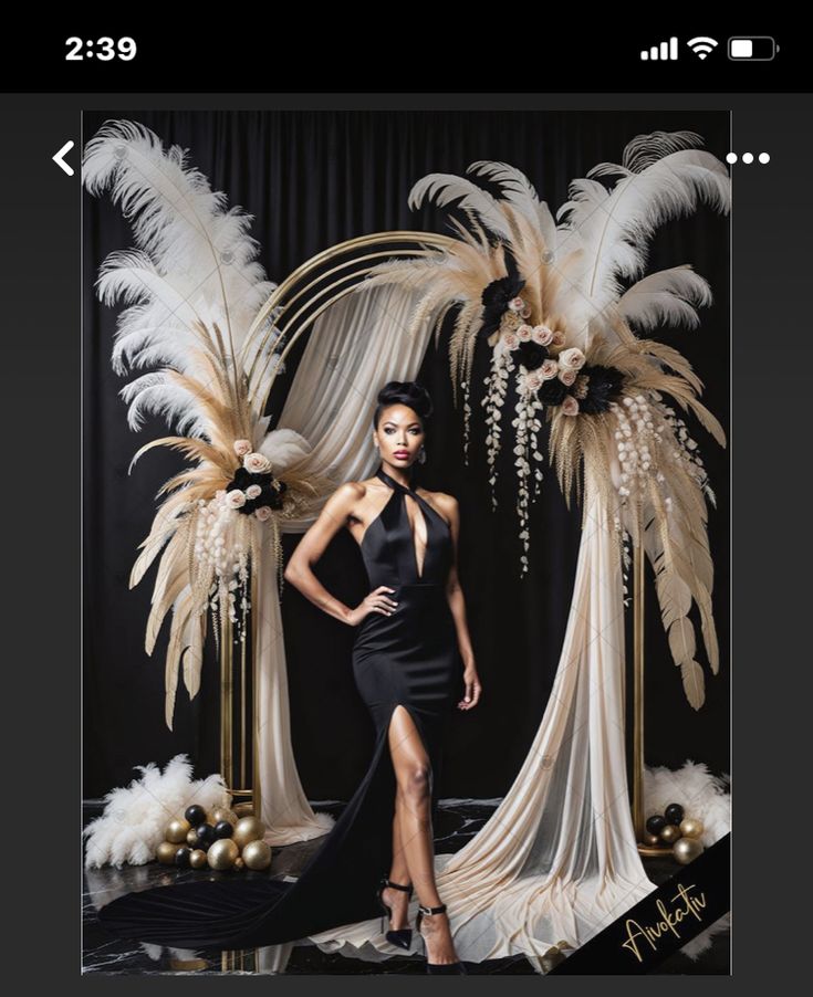 a woman in a black dress posing for a photo with feathers on the wall behind her