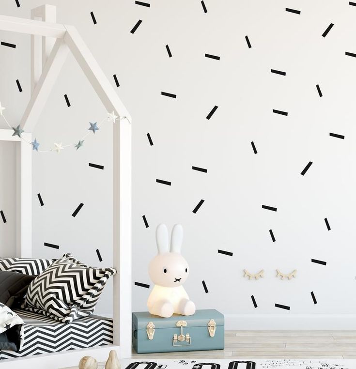 a white bed sitting next to a wall with black and white stripes painted on it