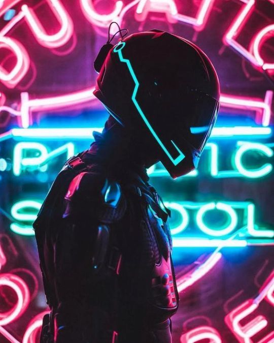 a man wearing a helmet standing in front of a neon sign