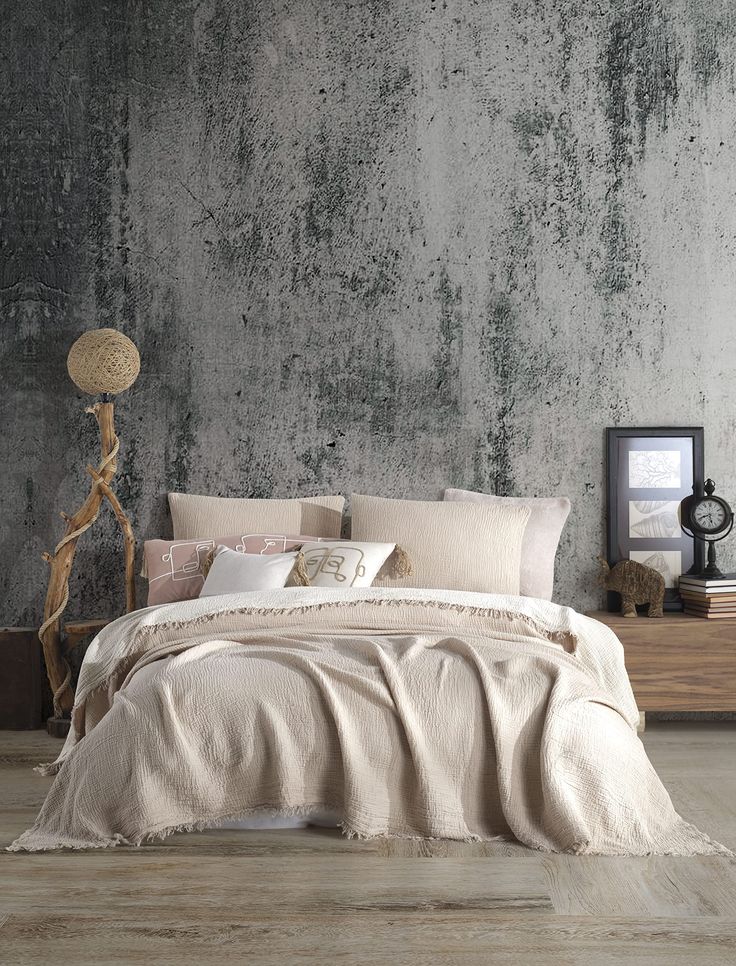 a bedroom with concrete walls and flooring is pictured in this image, the bed has been made up