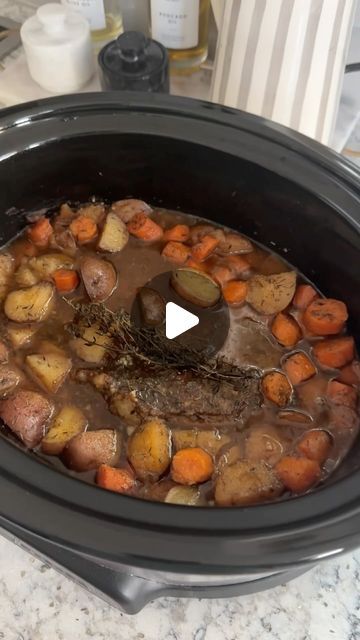 a slow cooker filled with stew and carrots