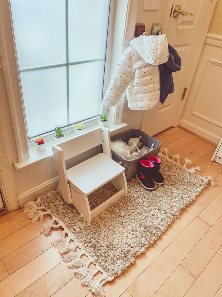 a cat sitting in a litter box on the floor next to a chair and window