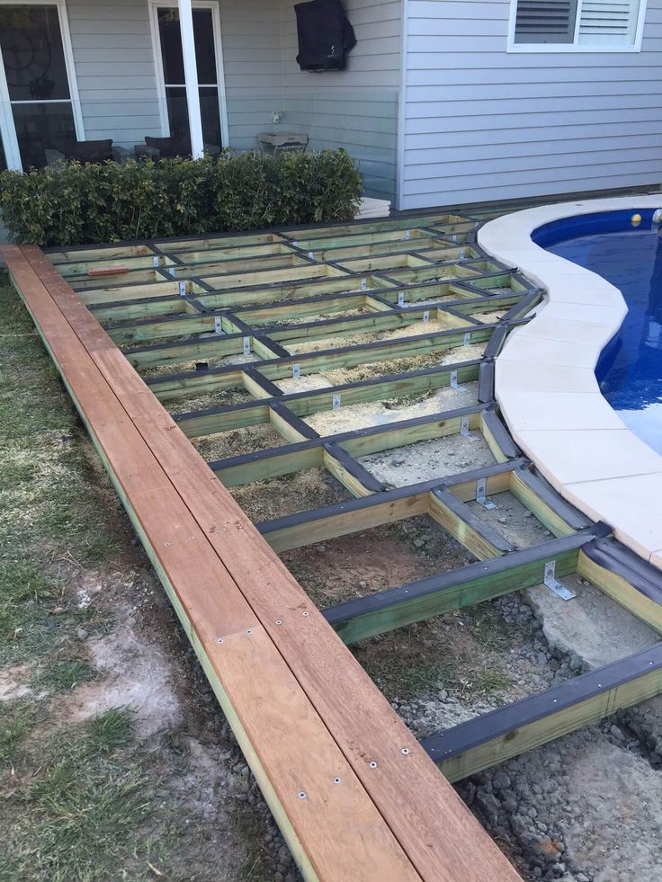 a pool being built in front of a house with a wooden deck and swimming pool