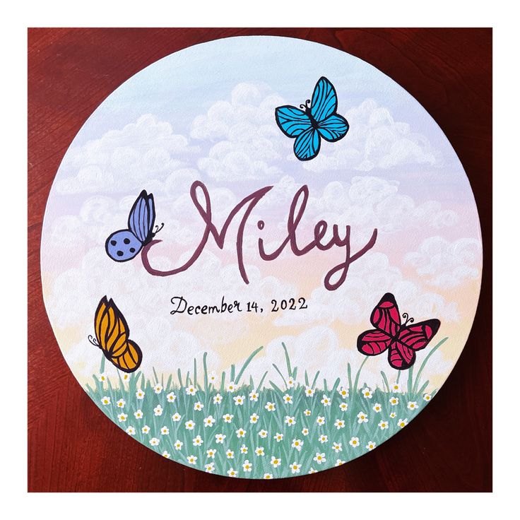 a personalized plate with butterflies and daisies in the grass on a wooden table