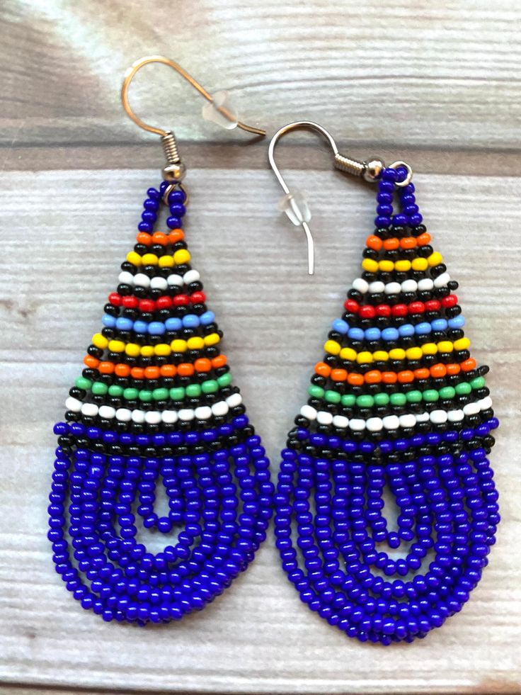 💫 Beautiful beaded earrings handmade in South Africa by Zulu women. 💫 Bold, bright ethnic colours, these earrings are a teardrop shape with intricate beading detail. 💫 Unusual, understated yet still glamorous! 💫 Each design is unique and hand beaded using traditional techniques. 💫 Earrings have a stainless steel, nickel-free hook and an additional rubber stopper. More about us Our products are all hand-made, by artists and crafters in South Africa. We source suppliers with the highest quali Traditional Multicolor Earrings With Large Beads, Traditional Multicolor Beaded Earrings, Traditional Colorful Festival Earrings, Colorful Traditional Earrings, Traditional Blue Beaded Earrings With Colorful Beads, Traditional Teardrop Beaded Earrings With Tiny Beads, Traditional Large Bead Drop Earrings, Traditional Blue Beaded Earrings, Traditional Multicolor Earrings With Colorful Beads