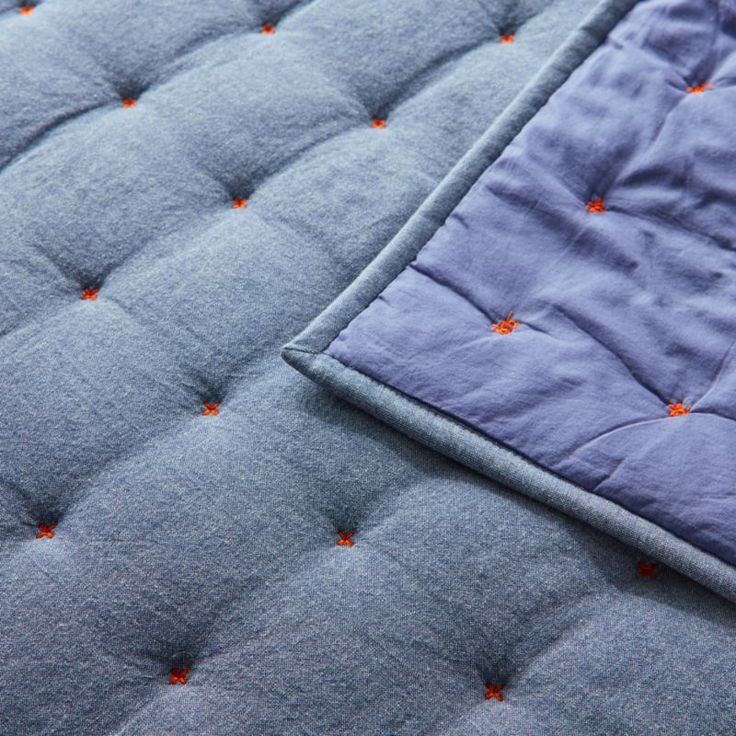 the blue quilted mattress has orange dots on it's edges and is folded down