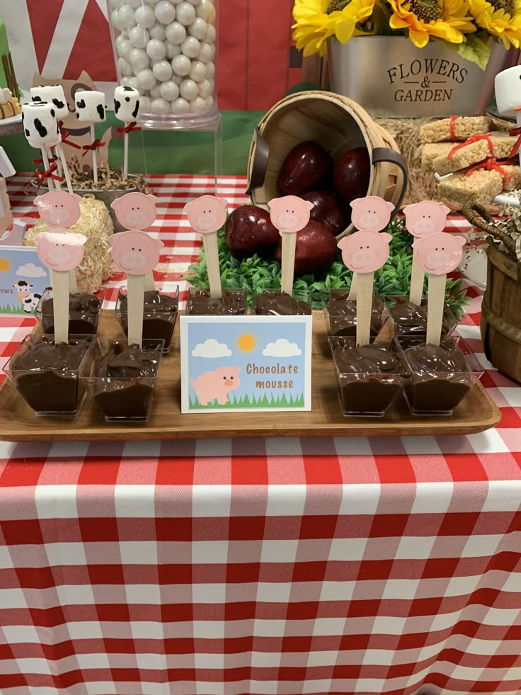 a table topped with lots of desserts and candies next to a red and white checkered table cloth