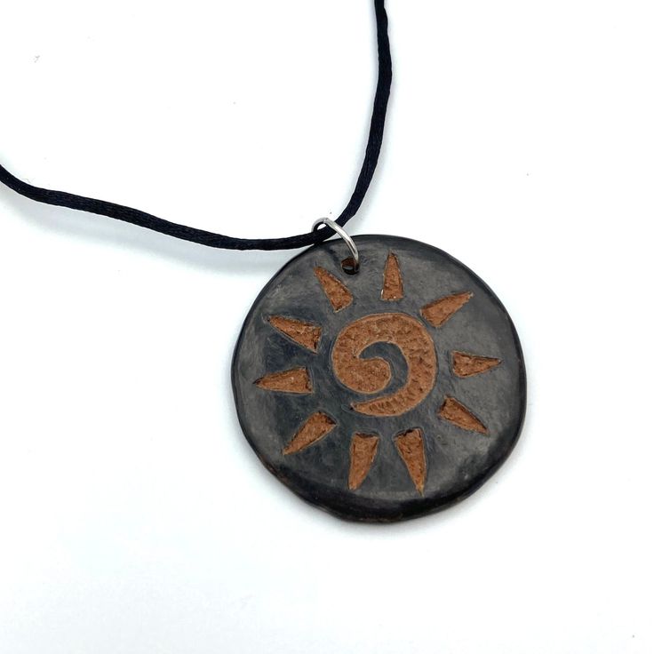 a black and brown necklace with an orange sun on it