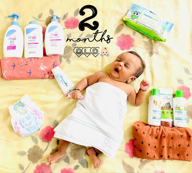 a baby laying on top of a blanket next to bottles of mouthwash and toothpaste