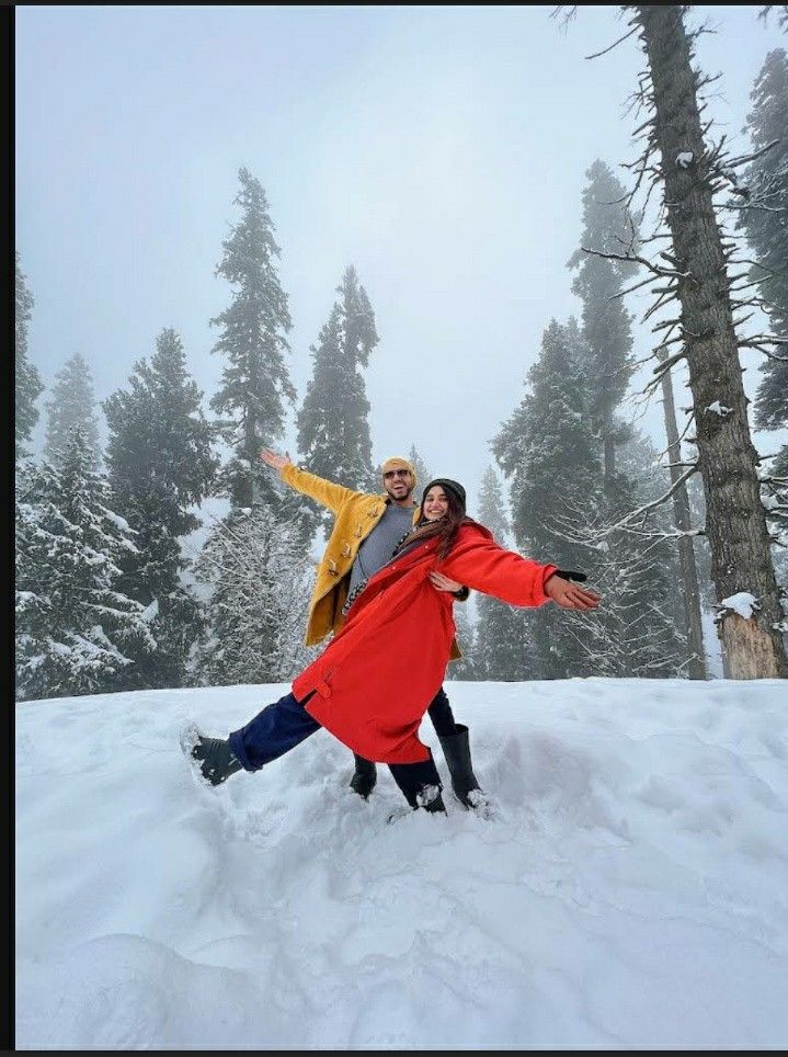 two people standing in the snow with their arms outstretched