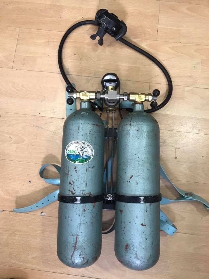 two blue cylinders are on the floor next to each other and one is connected to a hose