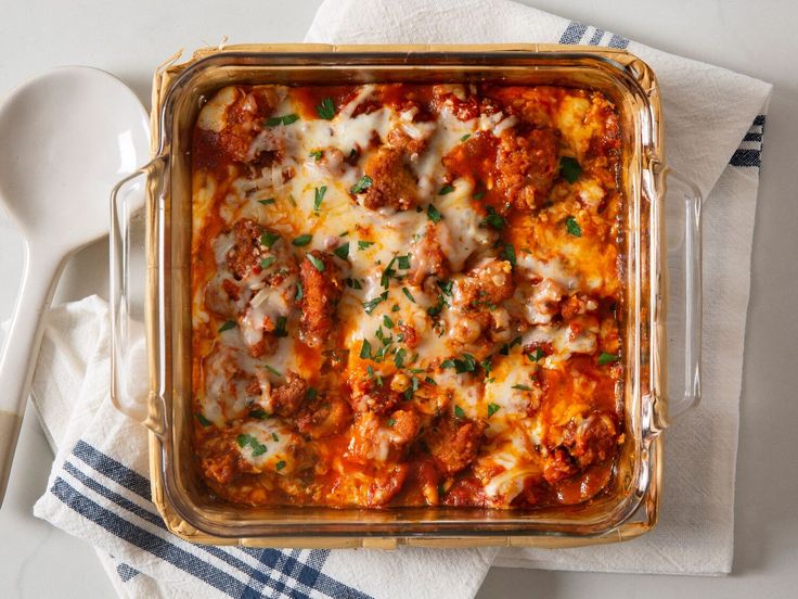 a casserole dish with meat and cheese in it on a napkin next to a spoon