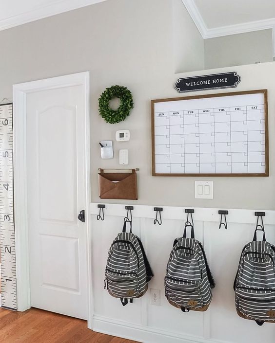 a white wall with three bags hanging on it and a ruler in front of it