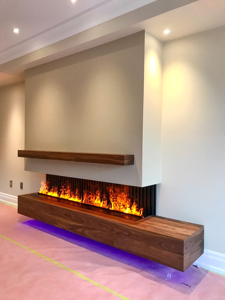 a modern fireplace in the middle of a room with no one around it and lights on