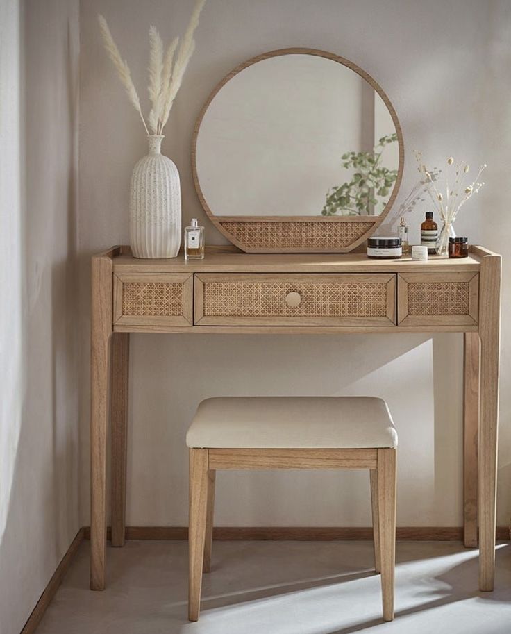 a wooden vanity table with a mirror and stool next to it in a white room