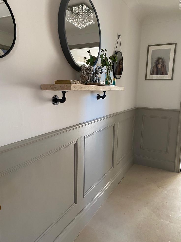 two mirrors hanging on the wall above a shelf