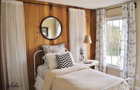 a bed room with a neatly made bed and a mirror on the wall above it