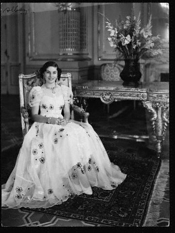 an old black and white photo of a woman in a dress sitting on a chair