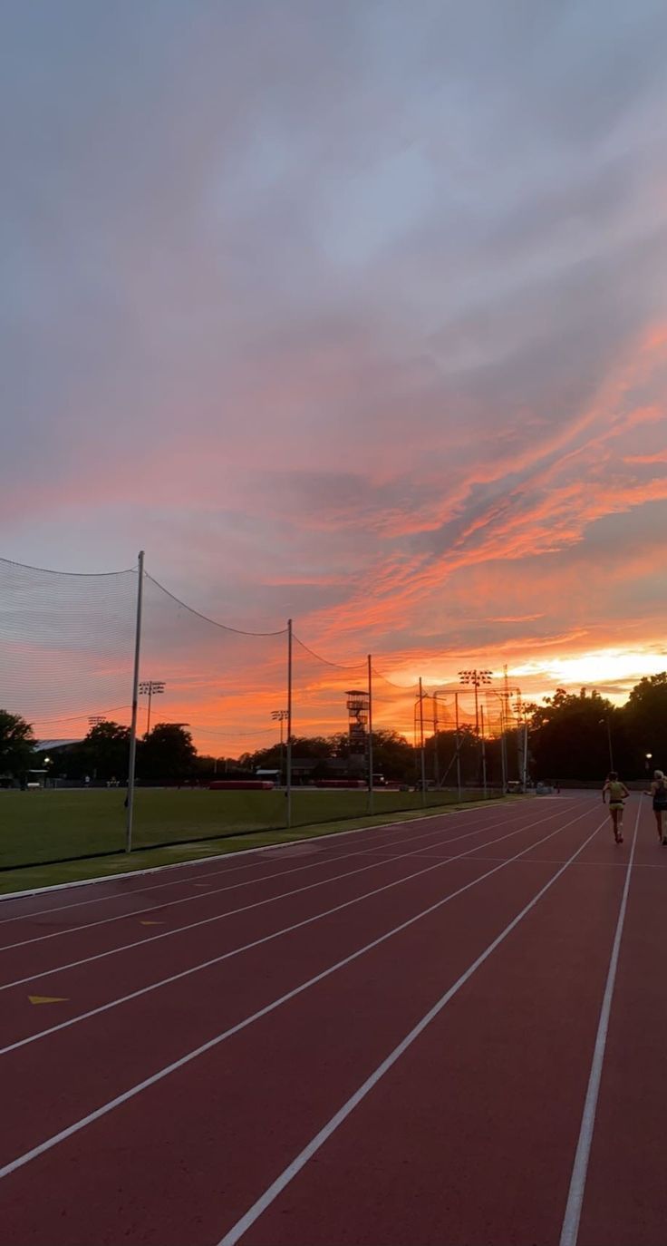 the sun is setting over an empty track