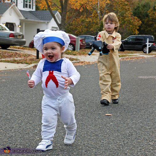 two children in costumes are running down the street