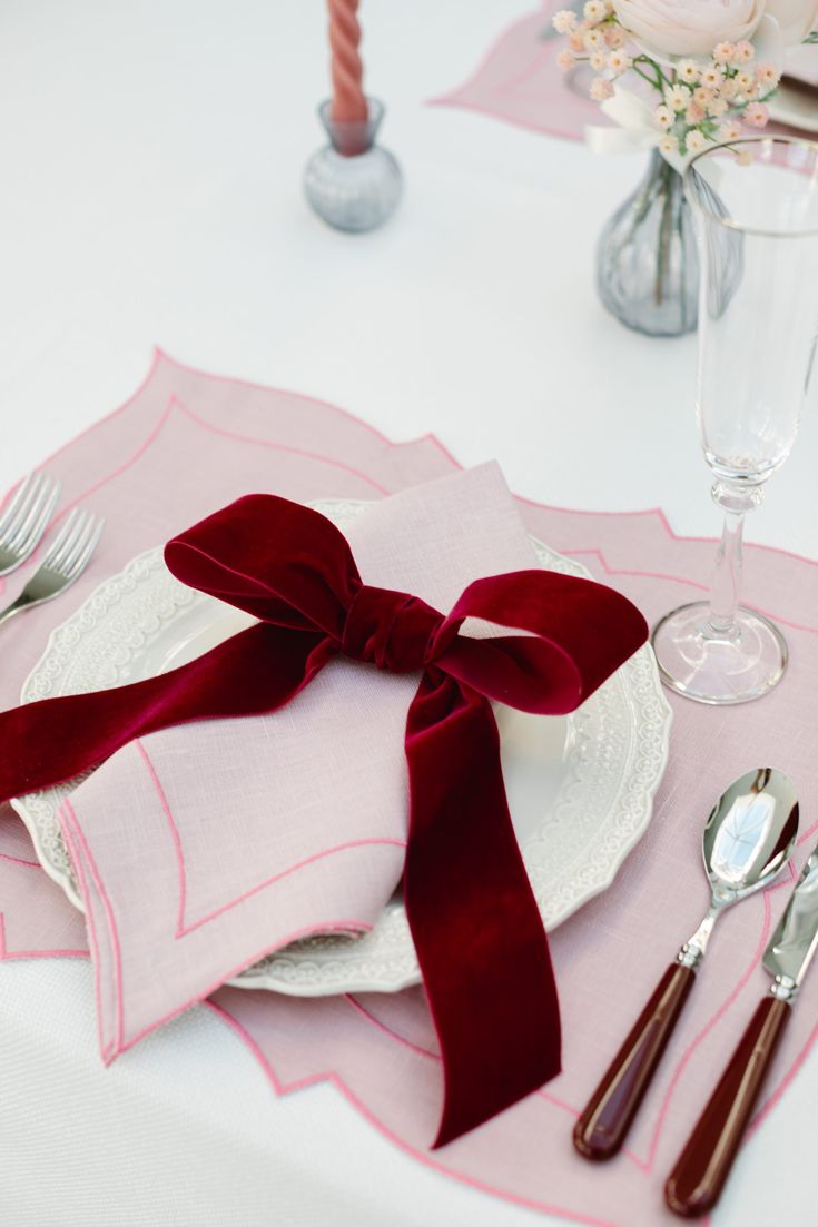 the table is set with silverware and napkins, along with red velvet bows