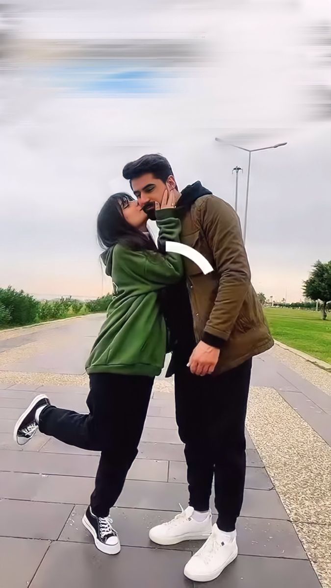 a man and woman standing next to each other on a sidewalk with their arms around each other