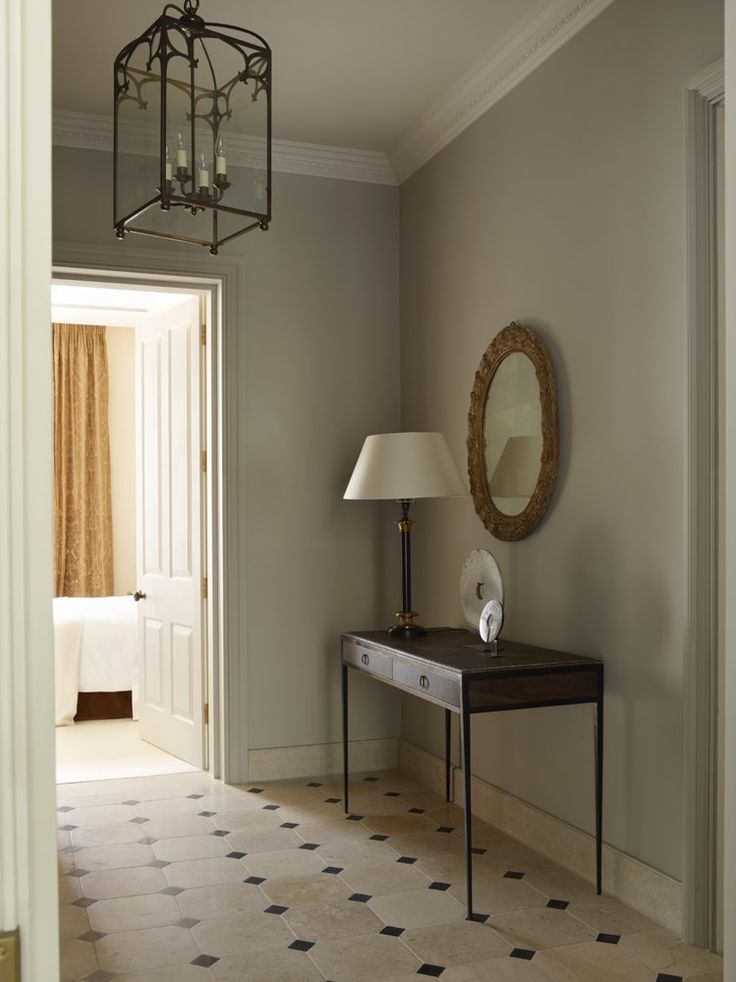 a room with a lamp, mirror and table in the corner near a door that leads to another room