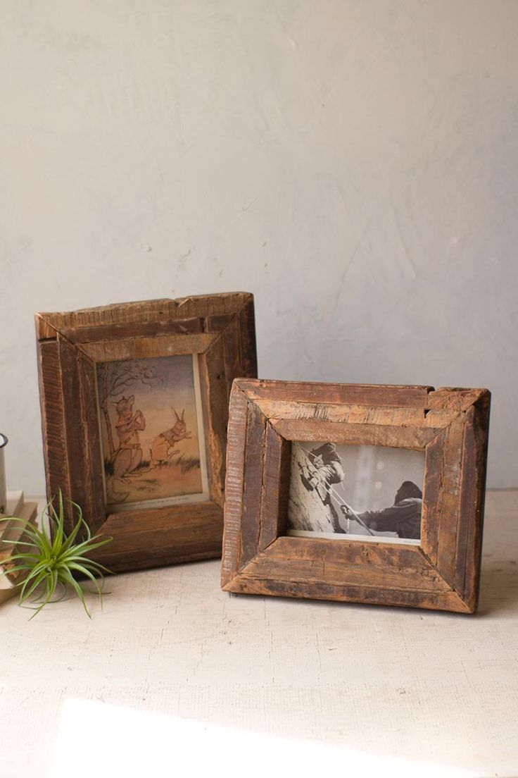 two wooden frames sitting on top of a table next to a potted green plant