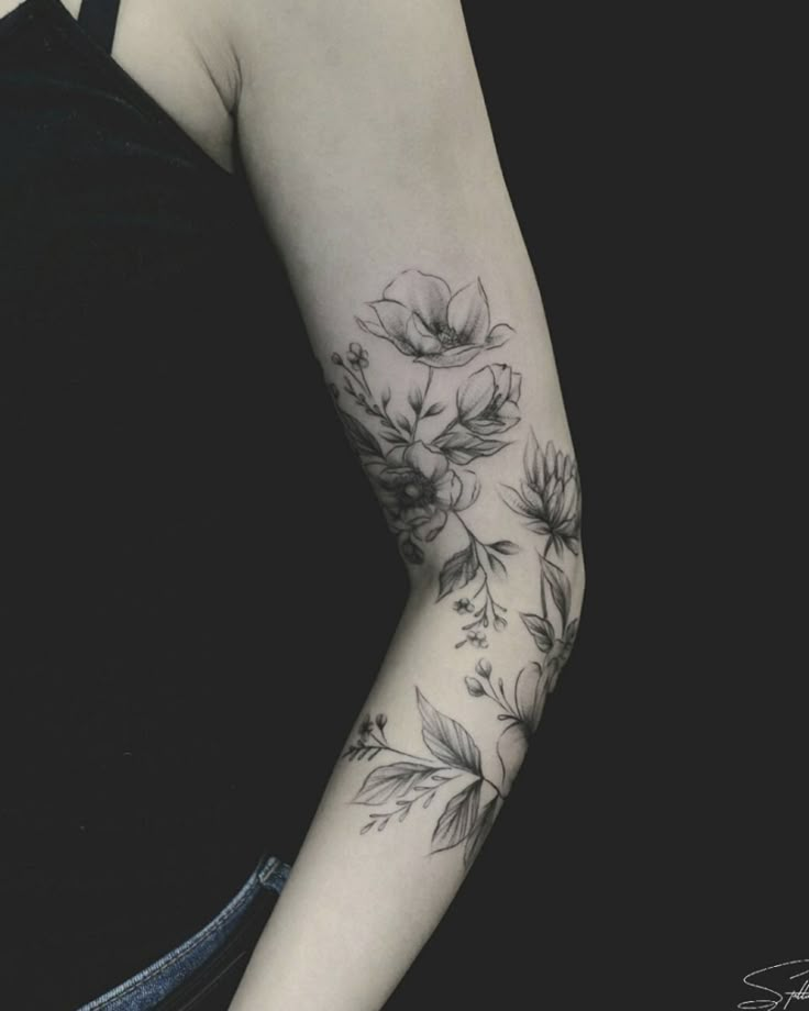 a woman's arm with flowers and leaves tattooed on her left arm, in black and white