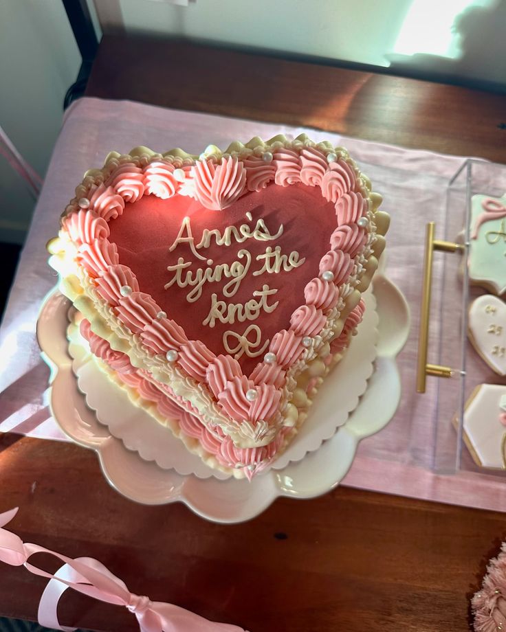 a heart shaped cake sitting on top of a table next to cookies and other decorations