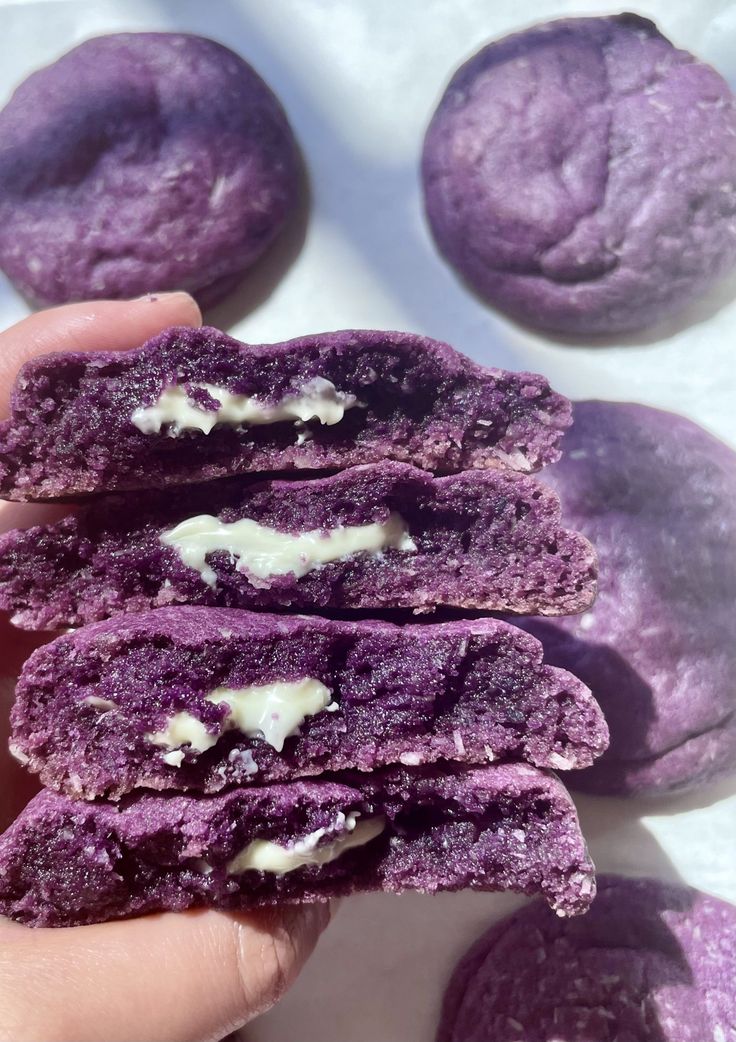 purple cookies with white filling being held by someone