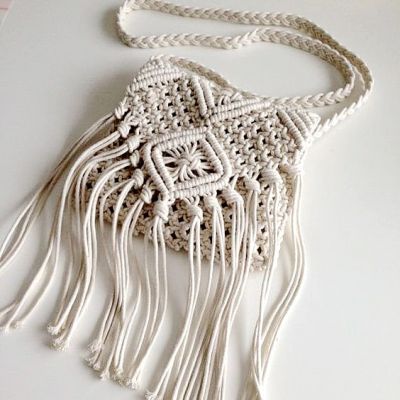 a white crocheted purse with tassels and beads hanging from it's side