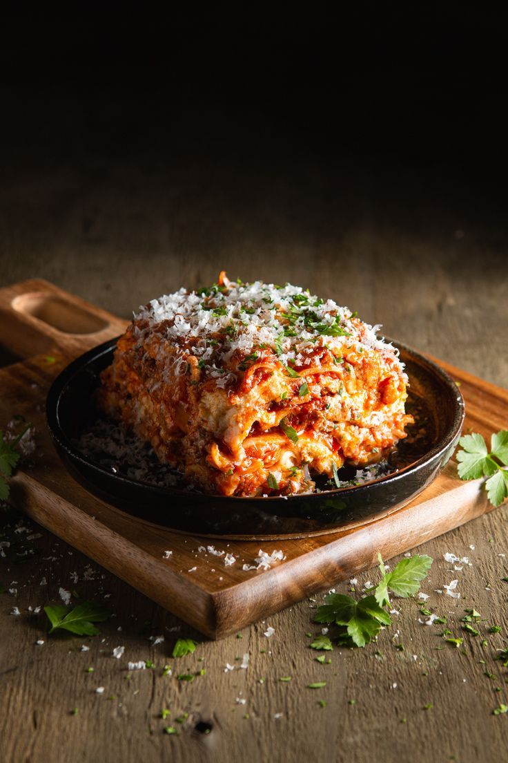 lasagna casserole with parmesan cheese and herbs on wooden cutting board