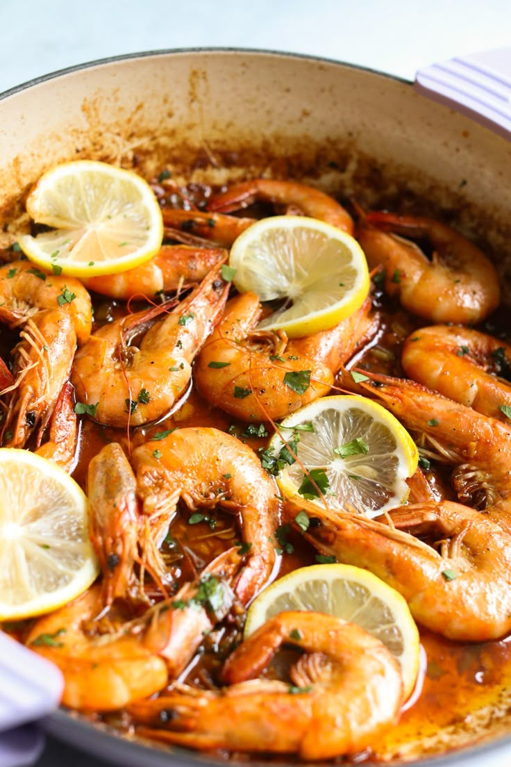 a pan filled with shrimp and lemons on top of a table