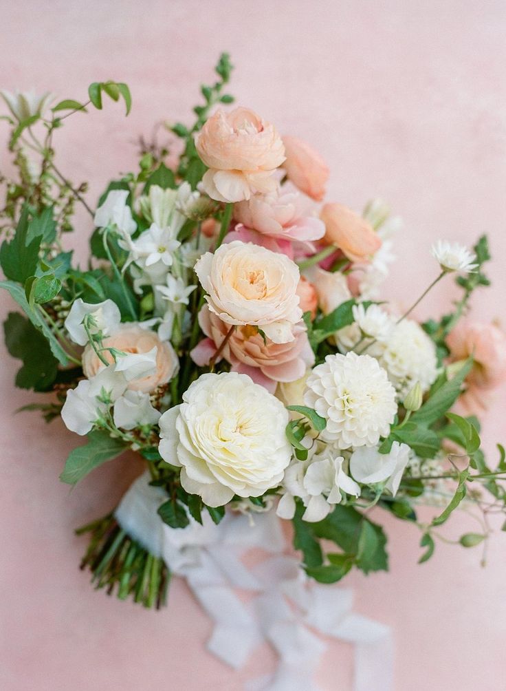 a bouquet of white and peach flowers on a pink background