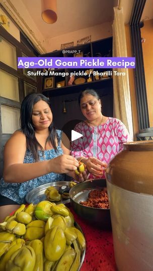 two women sitting at a table full of food and one woman is peeling an eggplant