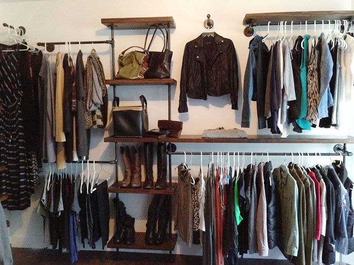 an organized closet with clothes, shoes and handbags hanging on the wall next to shelves