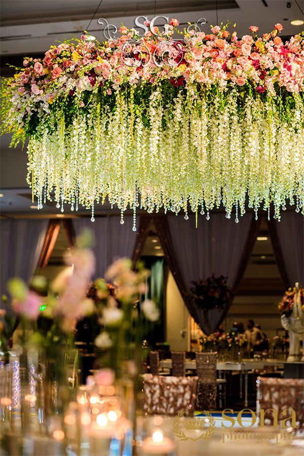 an elaborate floral arrangement hanging from the ceiling at a wedding reception with candles and flowers