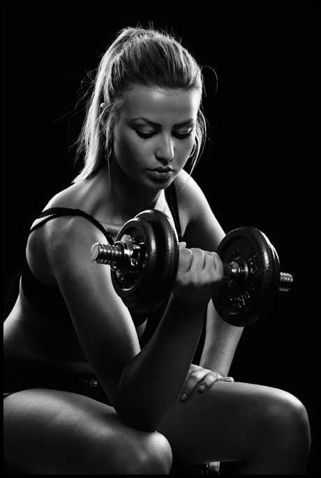 a woman squatting down with two dumbbells