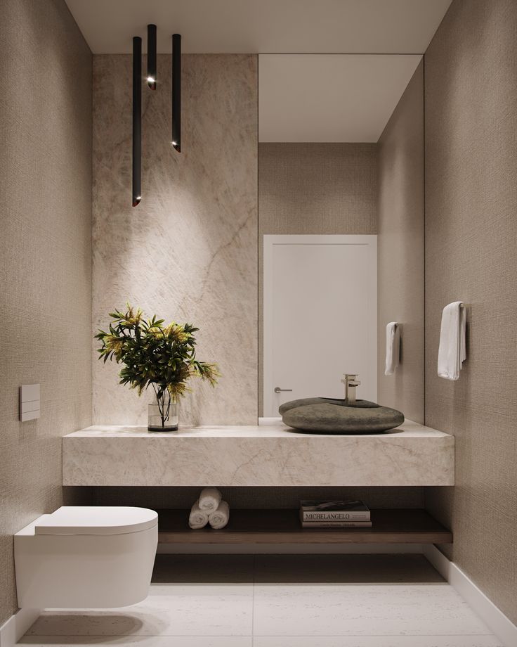 a white toilet sitting next to a bathroom sink under a mirror above a counter top