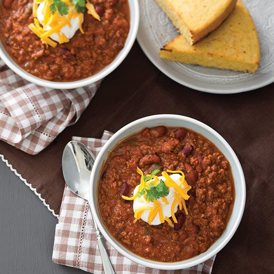 two bowls of chili with bread on the side