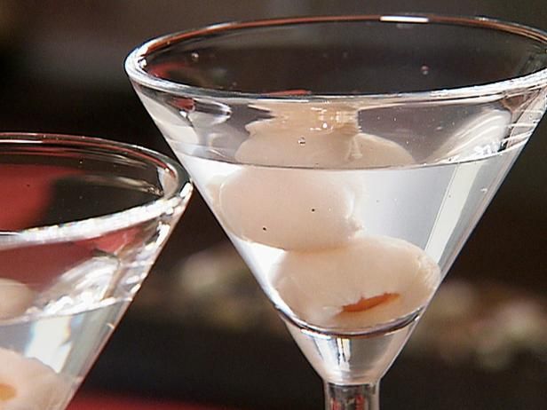 two martini glasses filled with white wine and ice cubes on the rim, next to each other