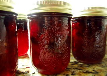 four jars filled with red liquid sitting on top of a counter