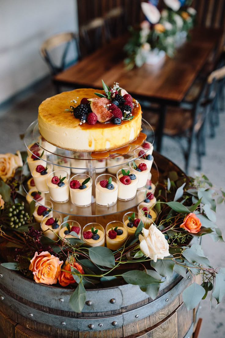 a three tiered cake sitting on top of a wooden barrel filled with desserts