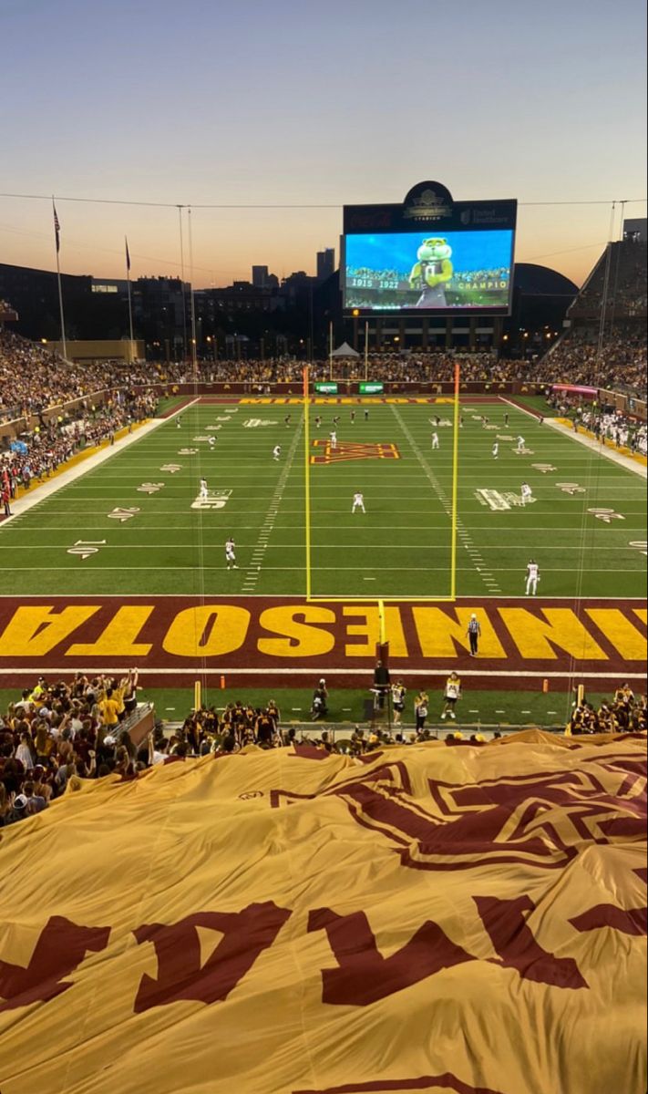 a stadium filled with lots of people sitting on top of a field next to a giant banner