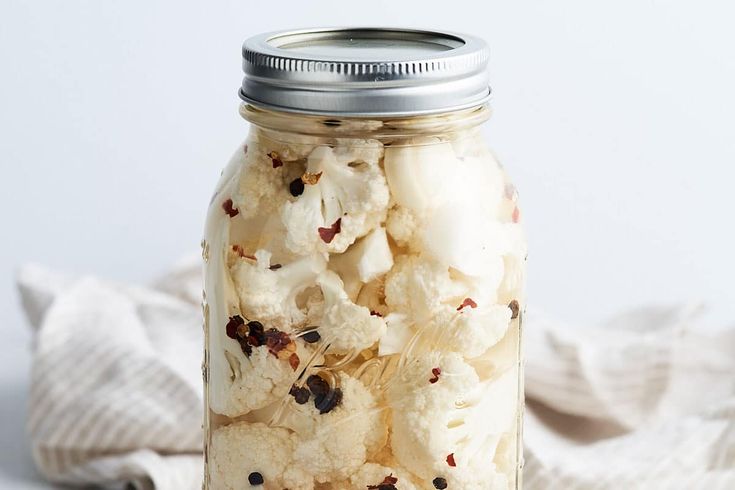 a glass jar filled with popcorn sitting on top of a white cloth covered tablecloth