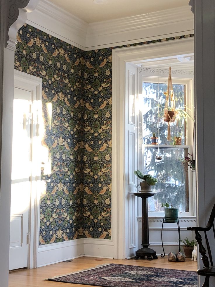 an empty room with a large window and floral wallpaper