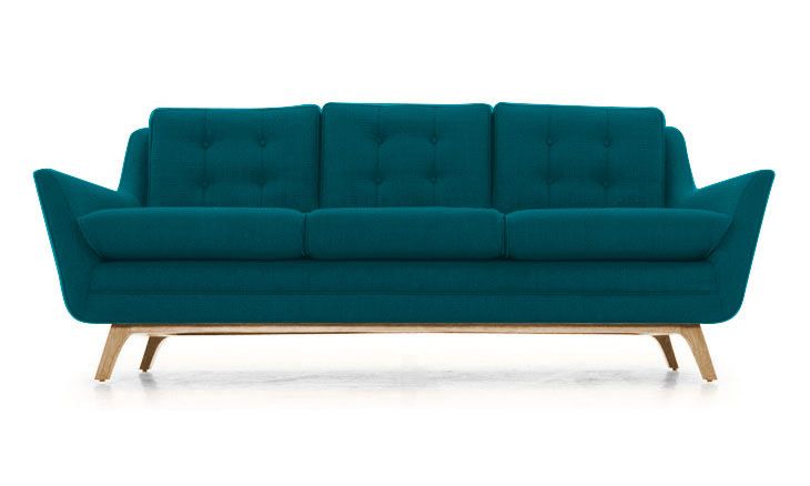 a blue couch sitting on top of a white floor next to a wooden leg chair