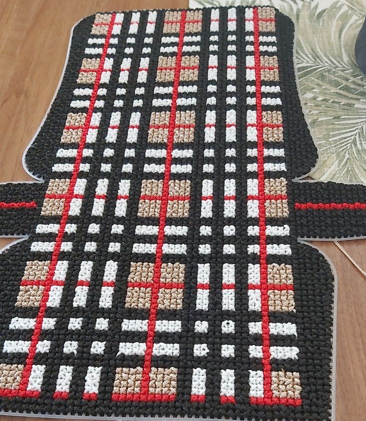 two black and red rugs sitting on top of a wooden floor next to a vase