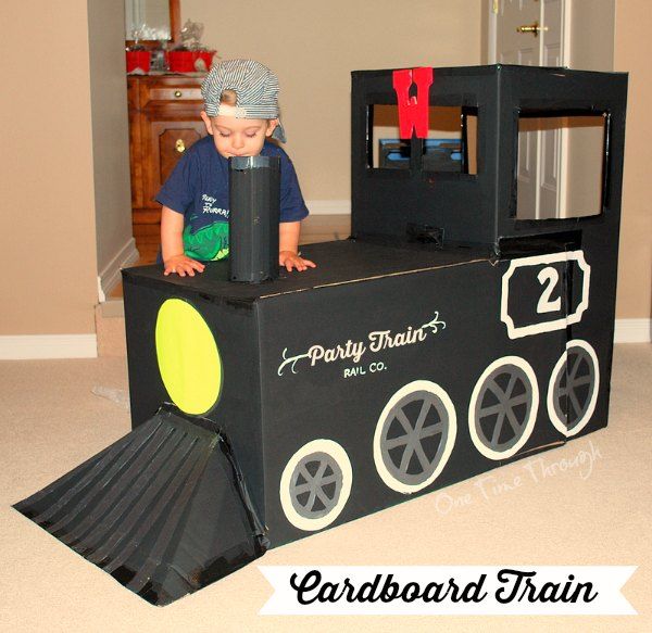 a young boy is playing with a train made out of cardboard